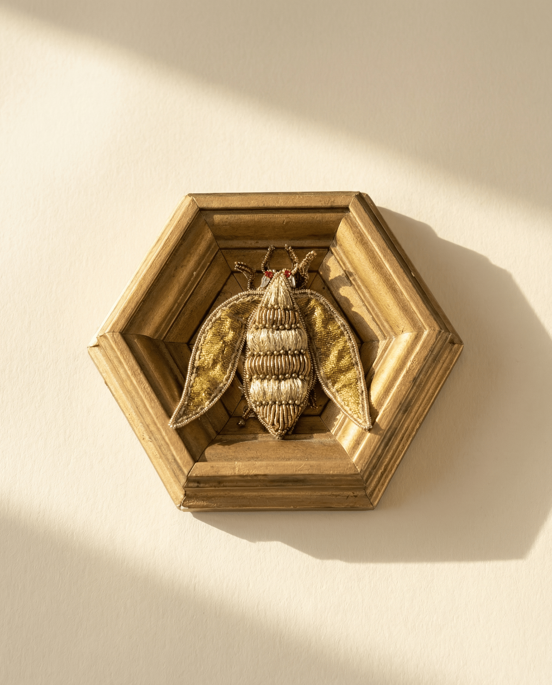 Decorative wall art with a framed insect on a beige background