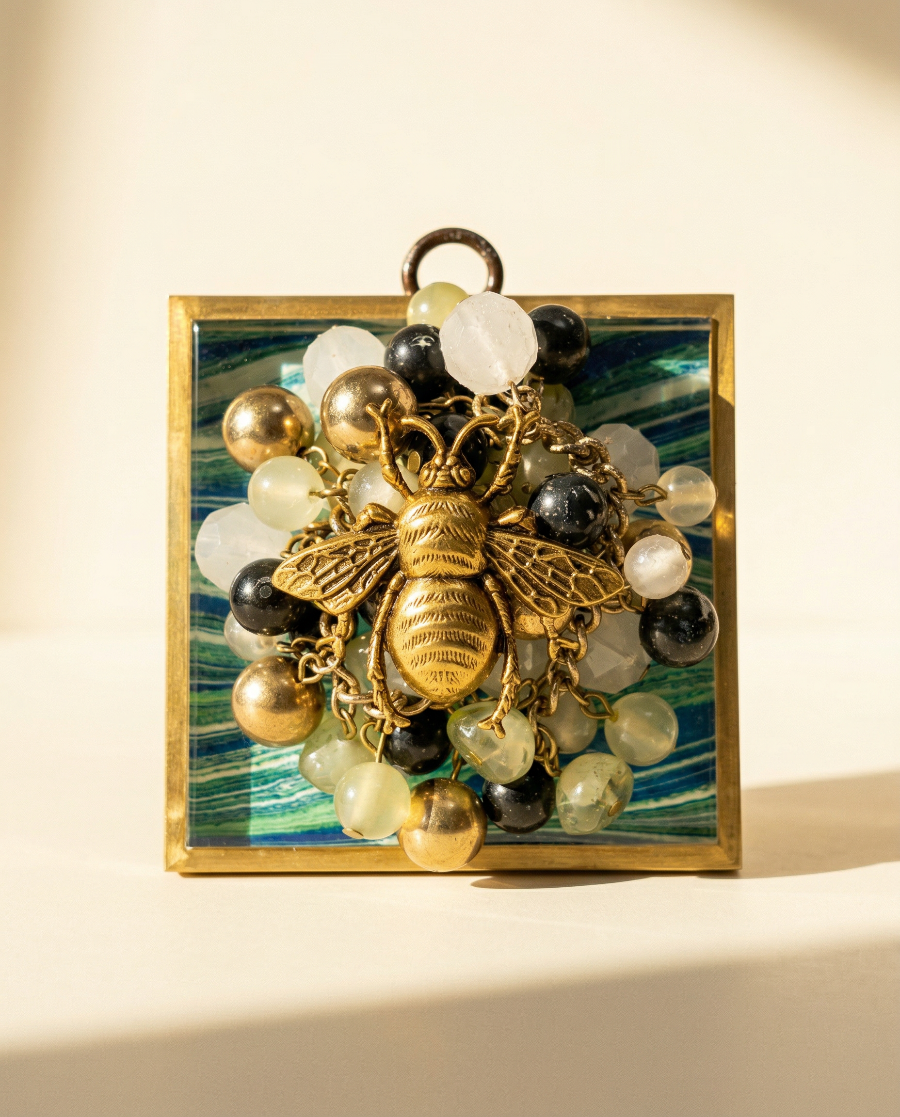 Decorative wall art with a gold bee and colorful beads on a blue and green acrylic frame 