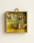 Decorative wall art with bee designs in a gold frame on a beige background