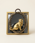 Decorative wall art with a gold cat figure on a black background, framed in bronze.