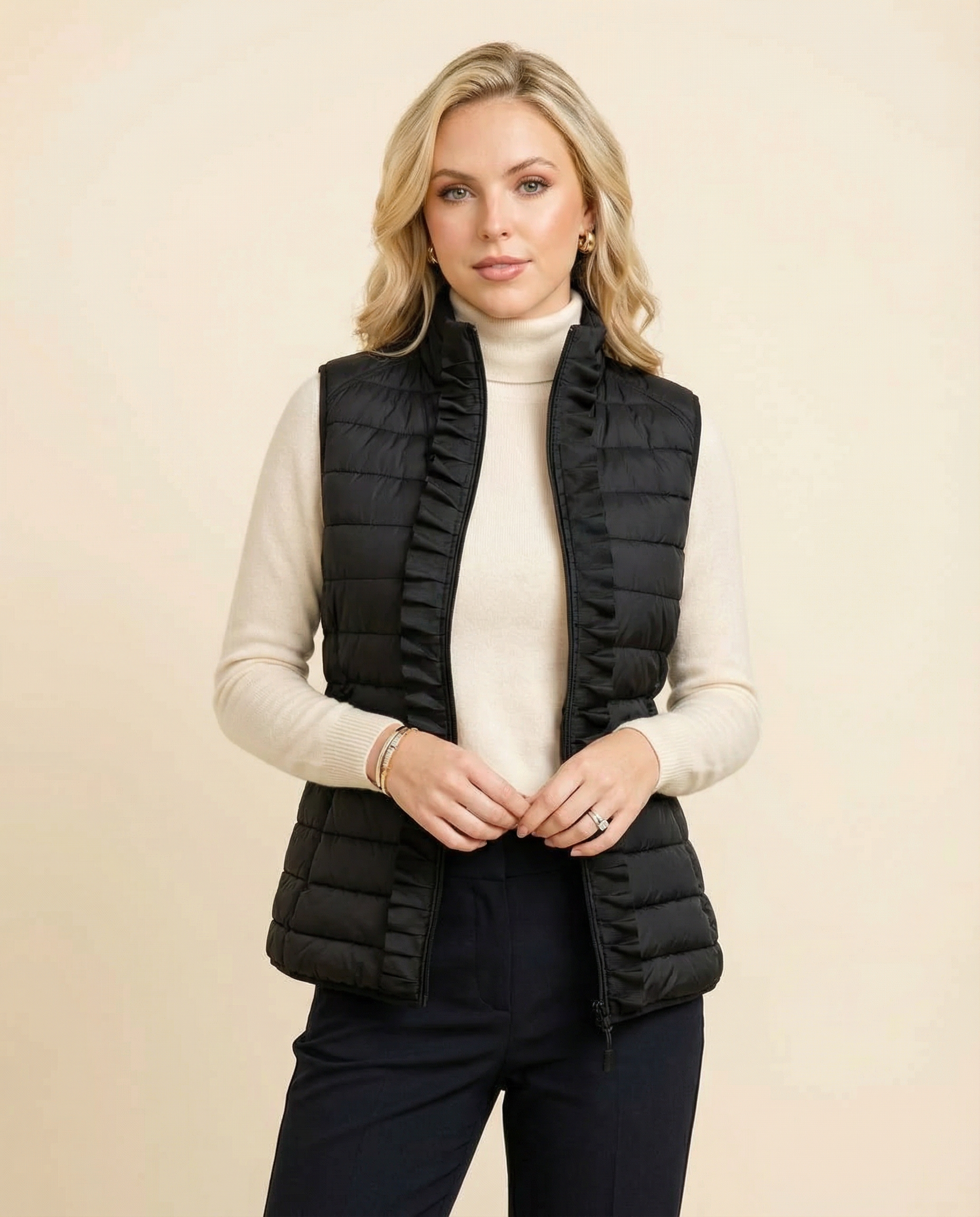 Woman wearing a black puffer vest over a white turtleneck on a beige background