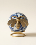 Decorative ceramic orb with a blue and white pattern and gold bee art