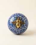 Decorative ceramic carpet ball with a gold bee emblem on white & blue art 