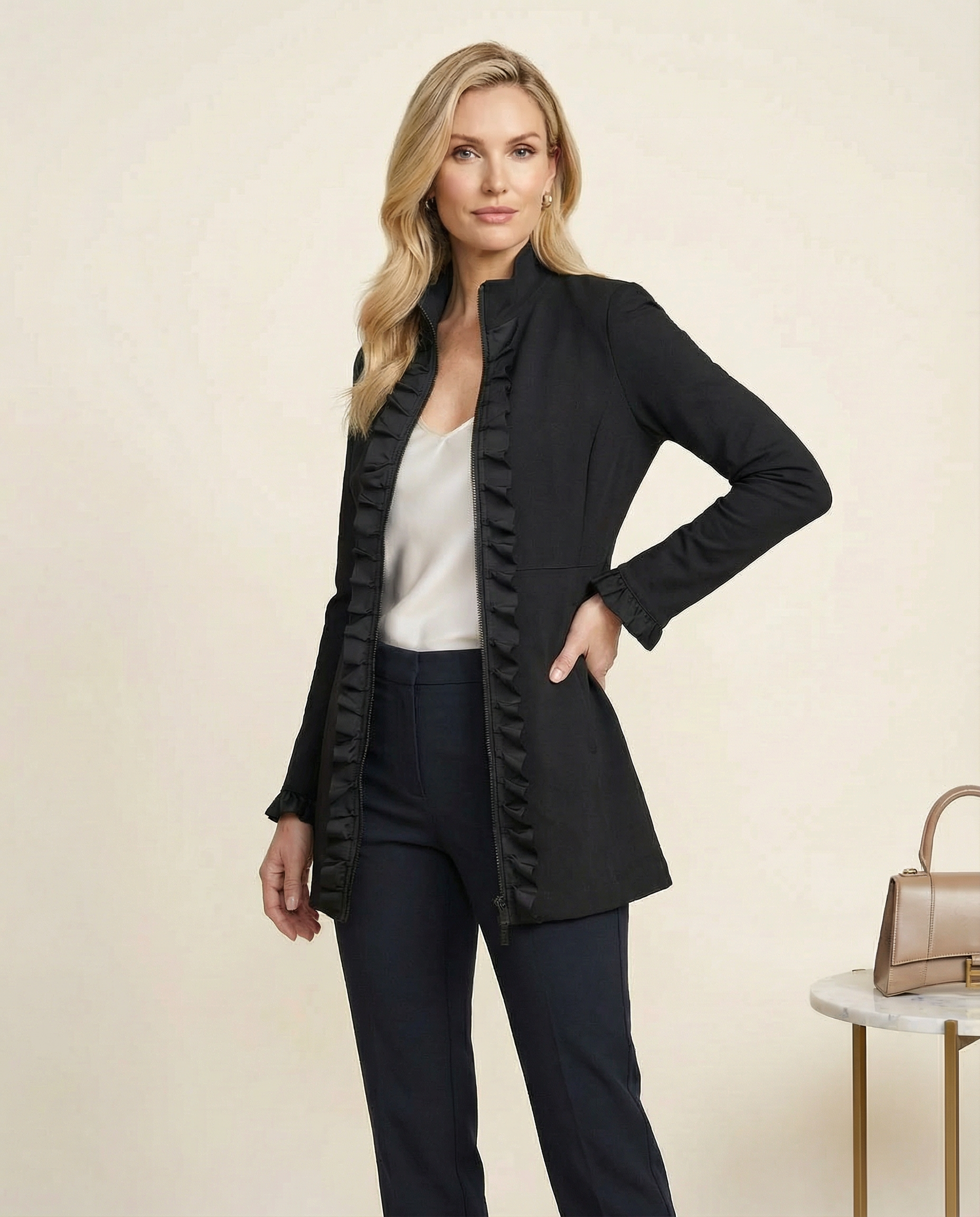 Woman wearing a black coat with ruffled details on a beige background