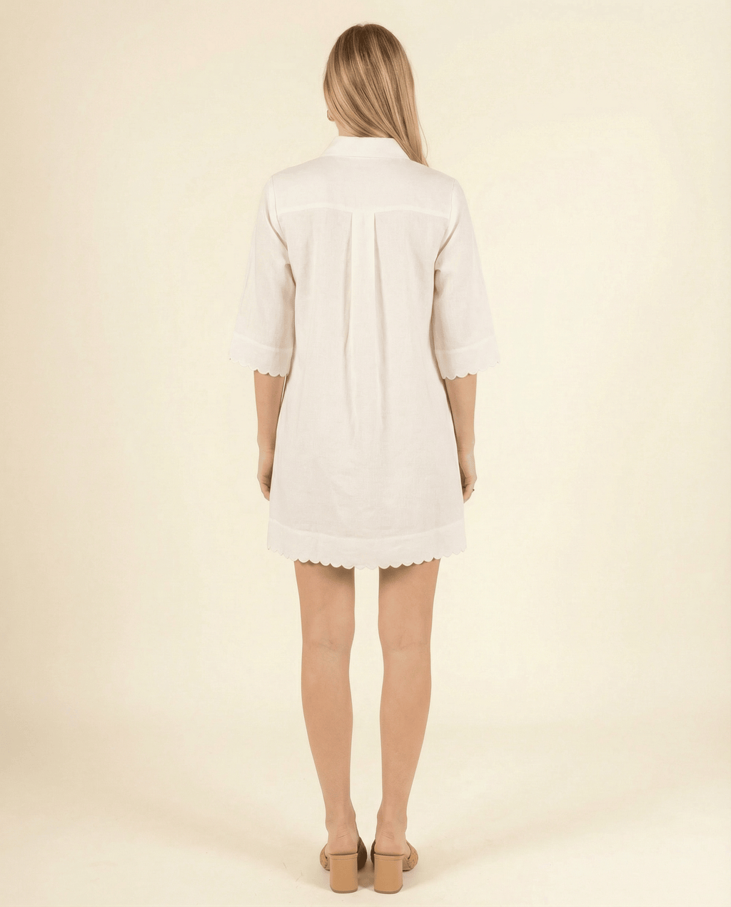 white cotton dress from the back side with a scallop hem