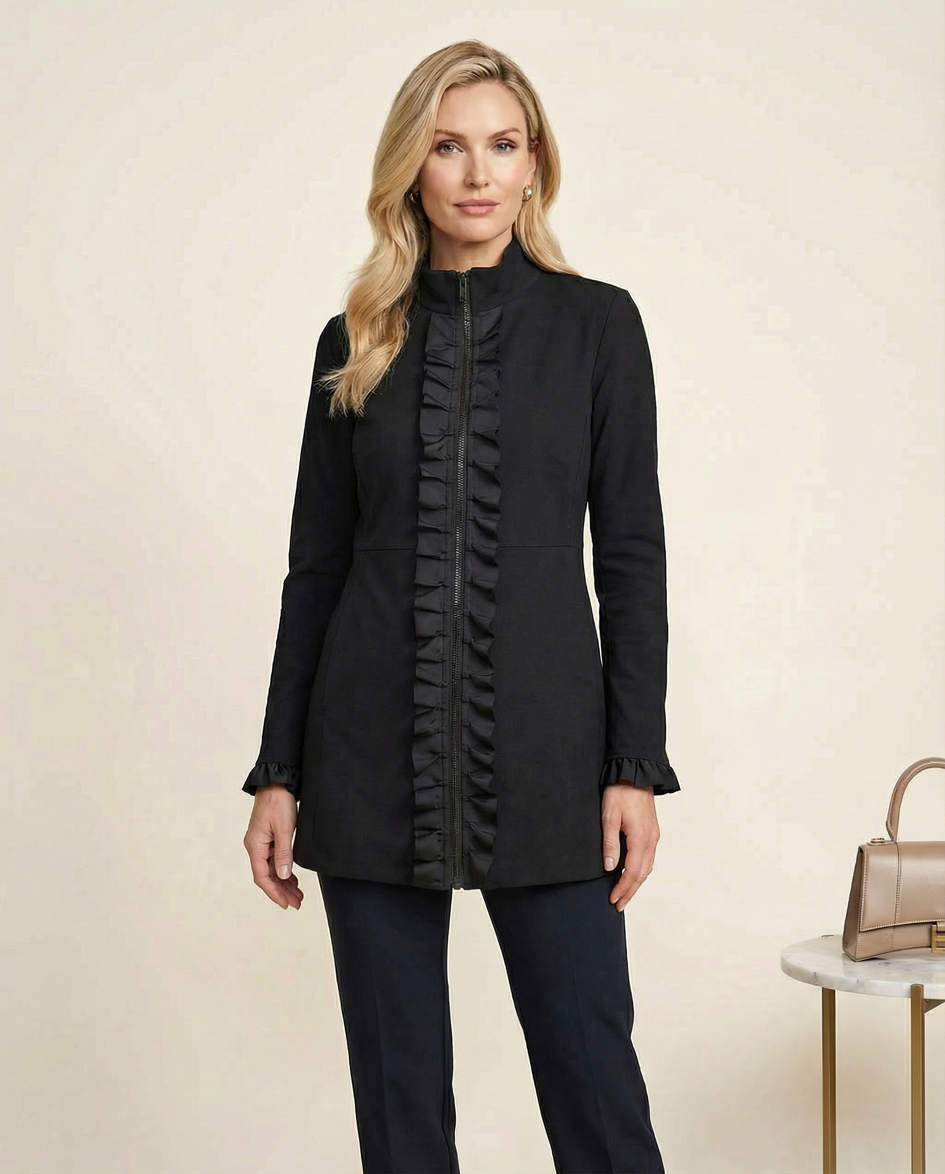 Woman wearing a black coat with ruffled details on a beige background