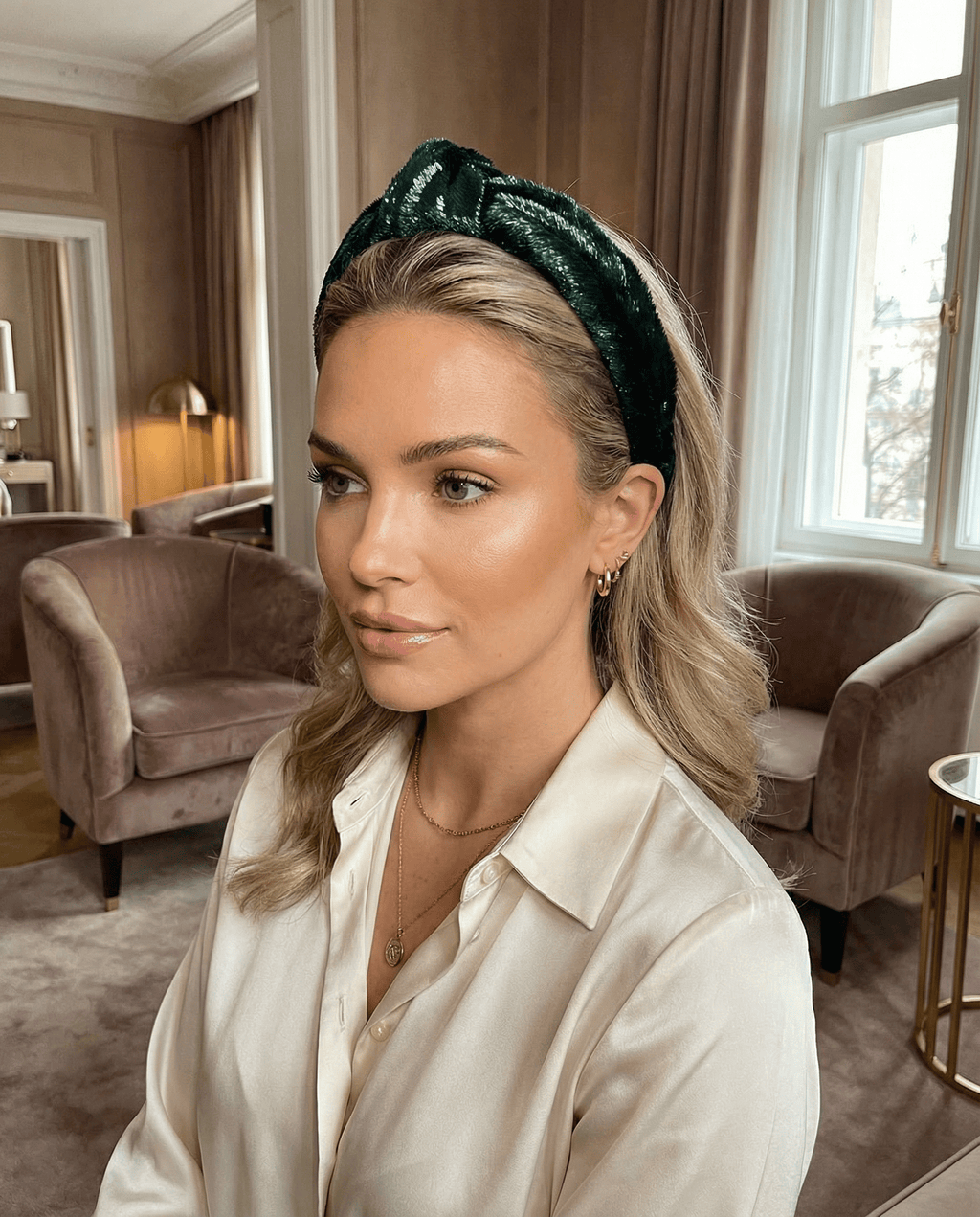 Woman wearing a green headband in an elegant room with furniture and decor.