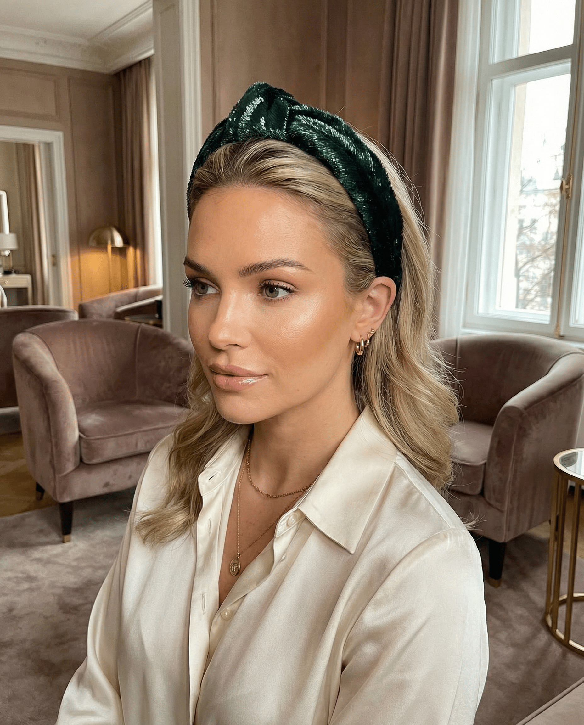 Woman wearing a green headband in an elegant room with furniture and decor.