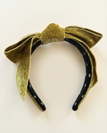 Gold and black headband with a large bow on a light beige background