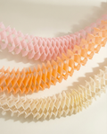 Three honeycomb party garland in pink, orange, and yellow on a white background