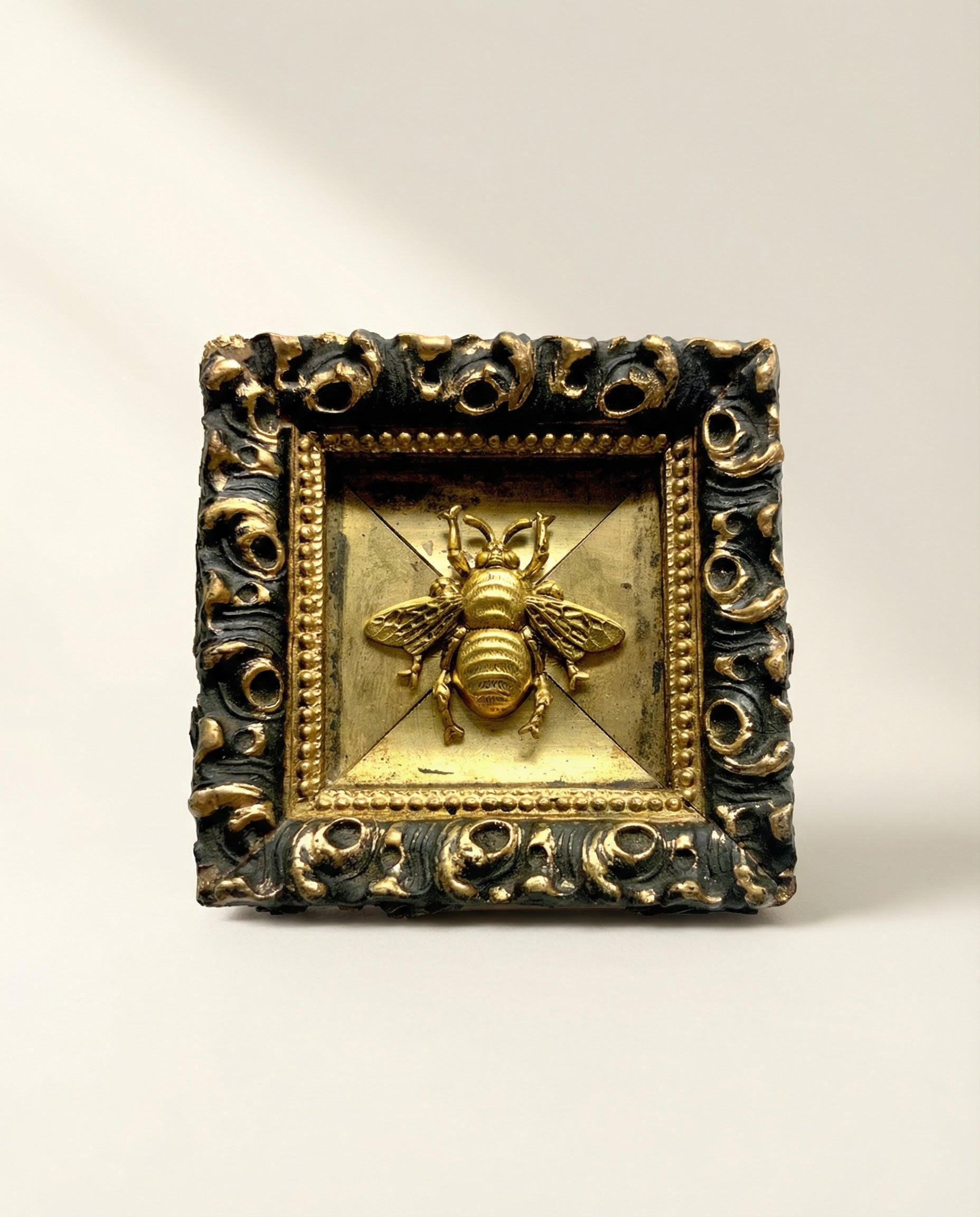Decorative art with ornate gold frame and bee emblem 