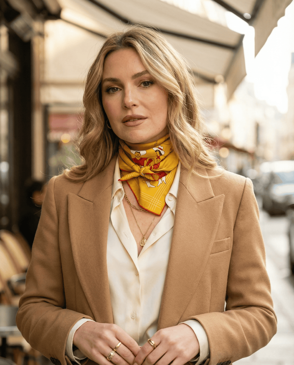 Woman wearing a beige blazer and colorful western scarf on a city street