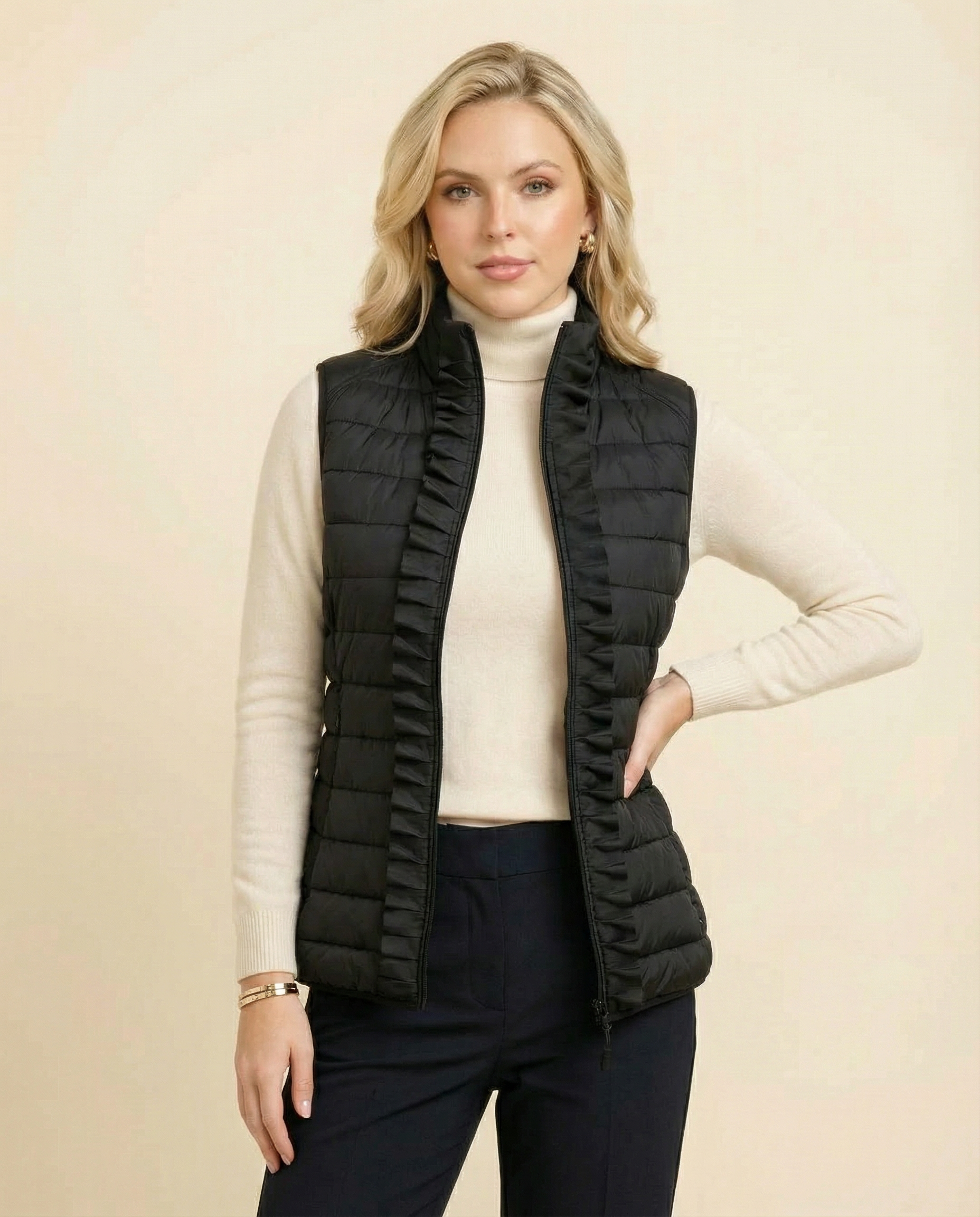Woman wearing a black puffer vest over a white turtleneck on a beige background
