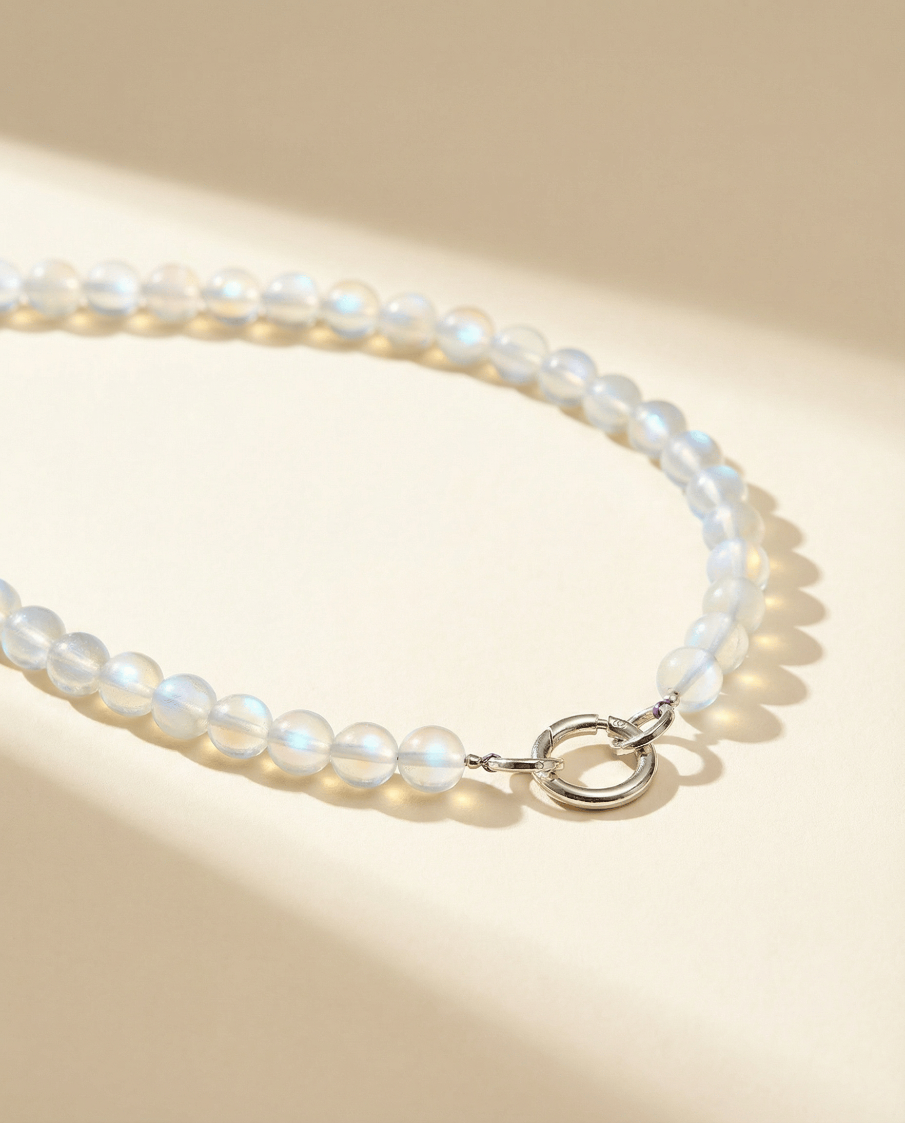 iridescent bead necklace with a silver clasp on a beige background