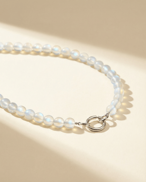 iridescent bead necklace with a silver clasp on a beige background