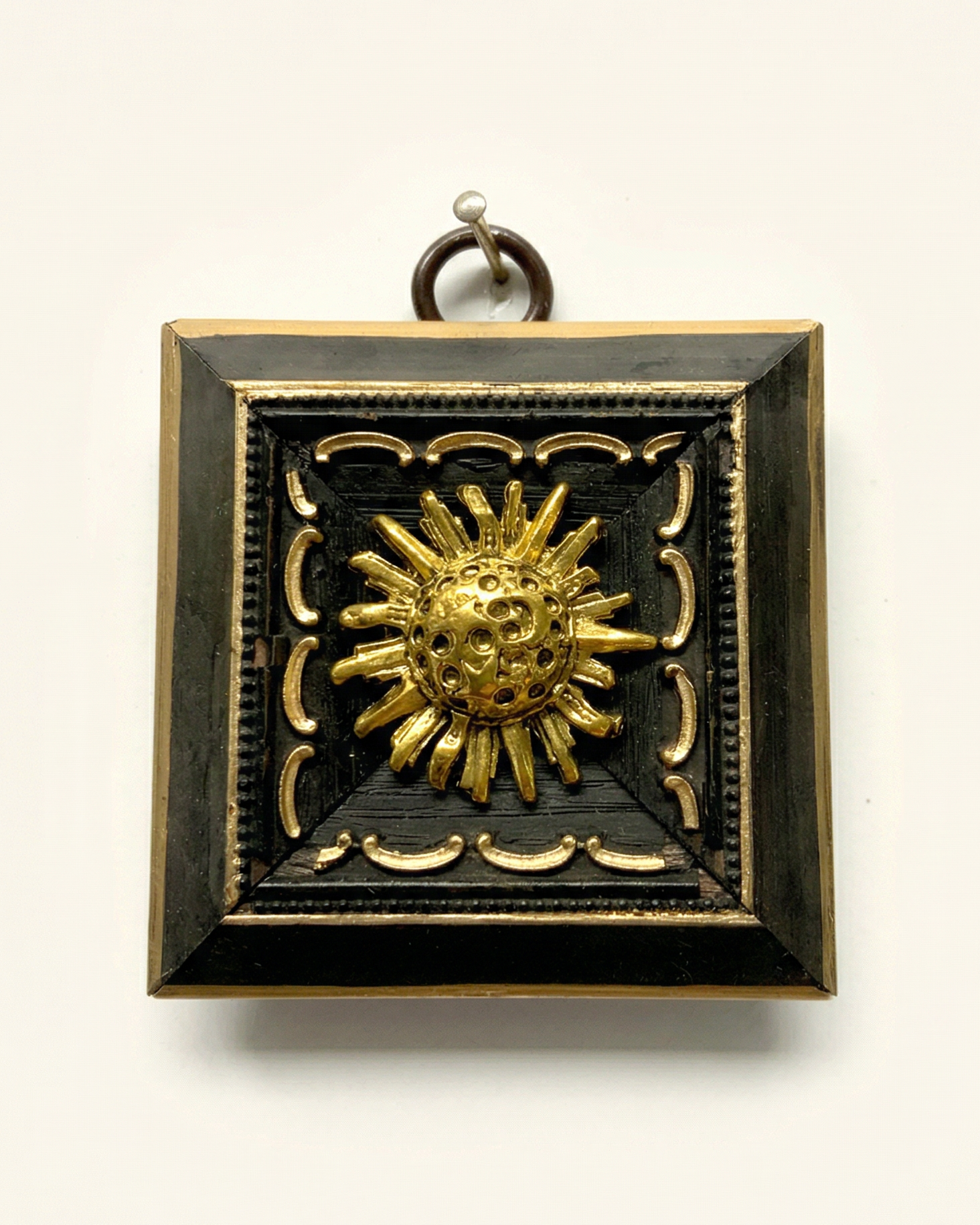 Decorative pendant with gold sun design on a black background